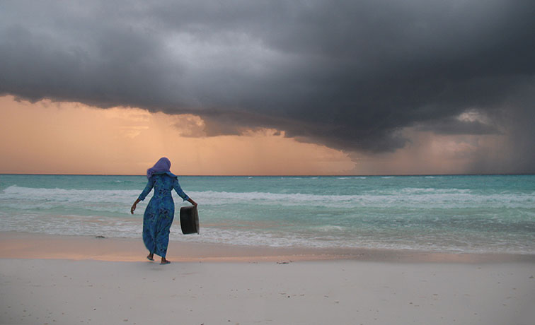 Bild: Frau am Strand bei aufziehendem Gewitter am Horizont